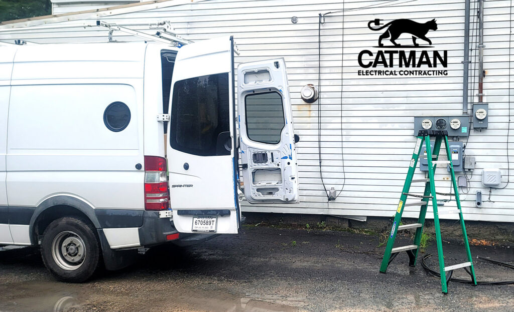 A white work van and a ladder next to exterior electrical meters on a building, representing Catman Electrical Contracting in Dallas, PA.