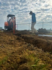 An electrician worker overseeing trenching for underground conduit installation by Precision Electric and Lighting Services in Olive Branch, MS.
