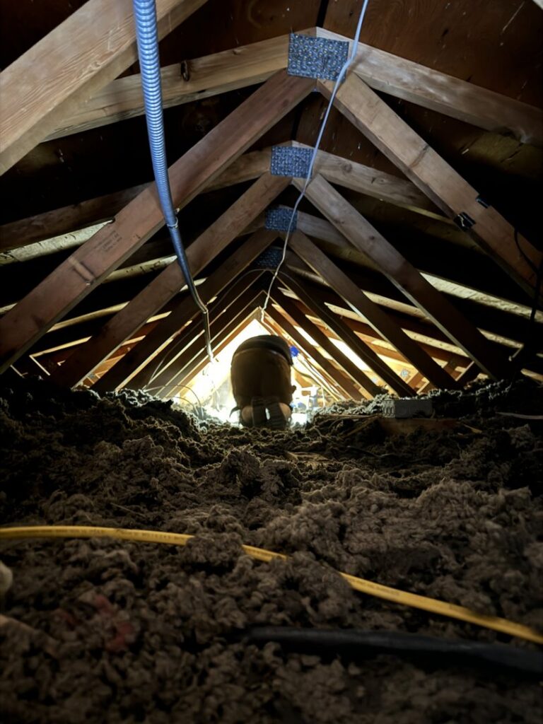 An electrician from P.H. Electric working on wiring in an attic space in Soulsbyville, CA.
