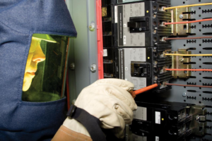 An electrician in arc flash gear working on a circuit breaker panel for Sterling Wiring Solutions in Pearland, TX.