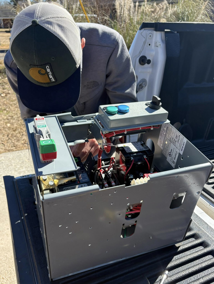 An electrician working on an open electrical control panel in a truck bed for Prescott Electric Service in Hattiesburg, MS.