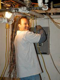 An electrician from Mendelson Electric working on an electrical panel and wiring in Pittsburgh, PA