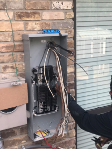 An electrician connecting wires in an open electrical panel for Pressed Down Electric LLC in Rockwall, TX.