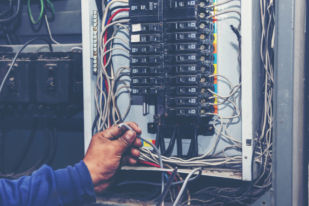 An electrician working on an open electrical panel with wires and circuit breakers for Right Electrical Services LLC in Raleigh, NC.