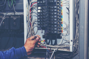 An electrician working on an open electrical panel with wires and circuit breakers for Right Electrical Services LLC in Raleigh, NC.