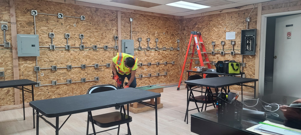 An electrician working on an electrical installation in a training facility at Millan Electric Service llc in Las Vegas, NV