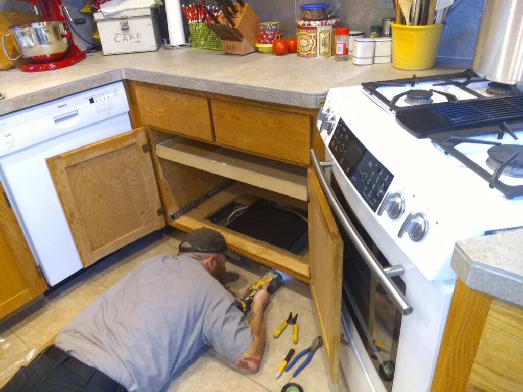 An electrician from Vets Electric Company working on kitchen wiring under a cabinet in Tacoma, WA