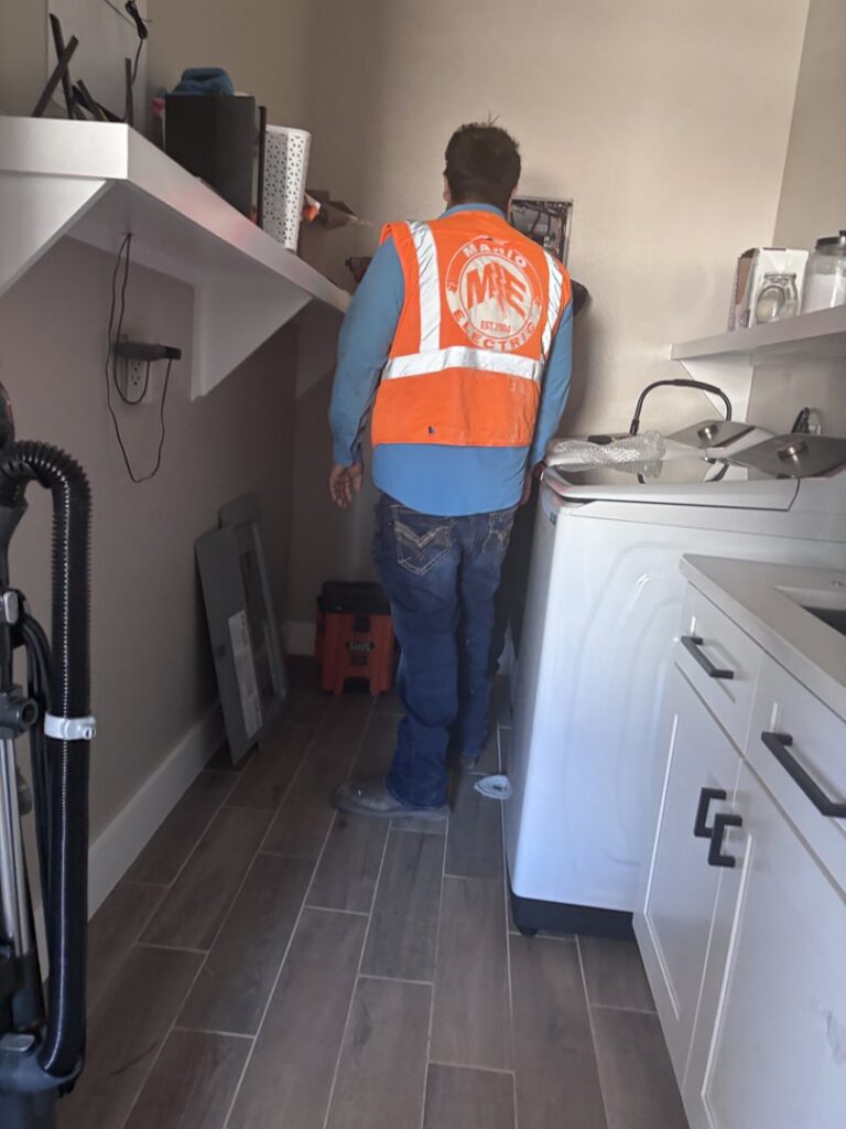 An electrician from Mario Electric working on wiring in a laundry room in San Antonio, TX.