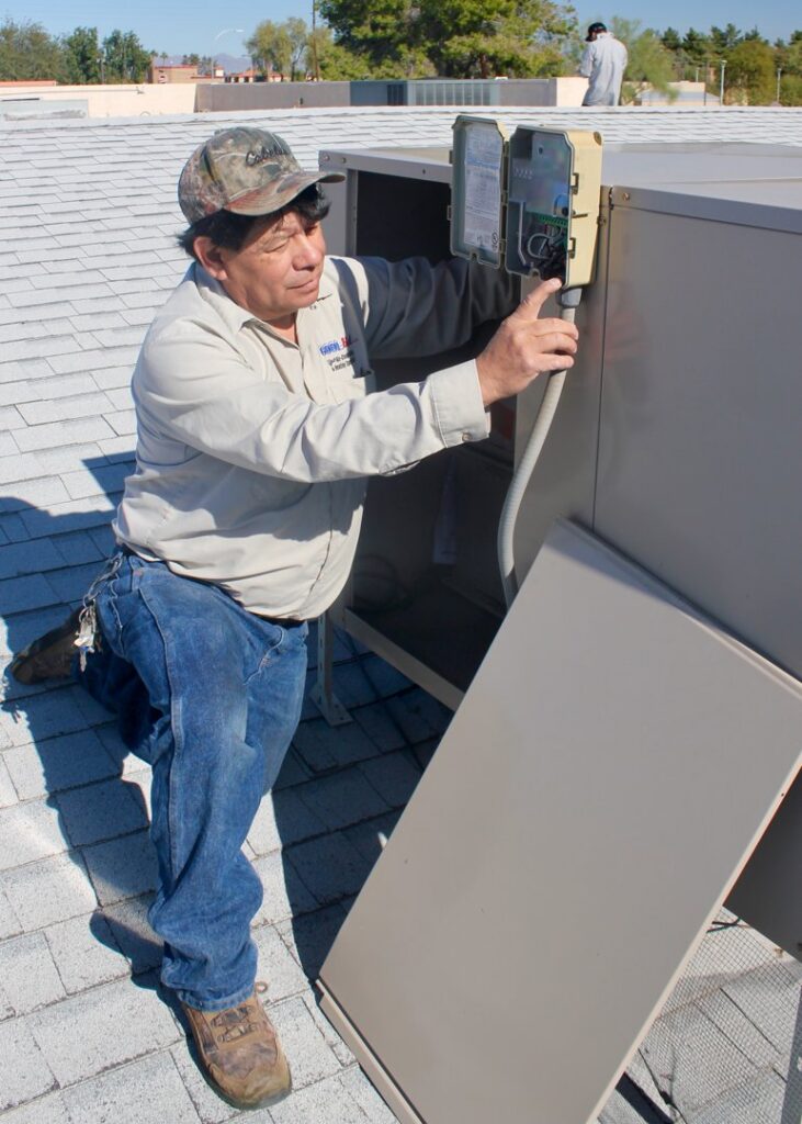 An electrician working on an AC unit's electrical disconnect box with a screwdriver for Cool Aid Air Conditioning in Scottsdale, AZ