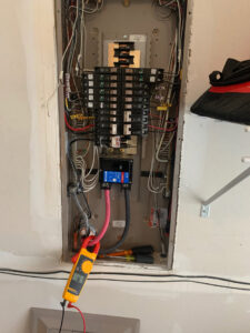 An electrician from IRV Plumbing, Electric & HVAC working on an open electrical breaker panel with a multimeter in Charlotte, NC