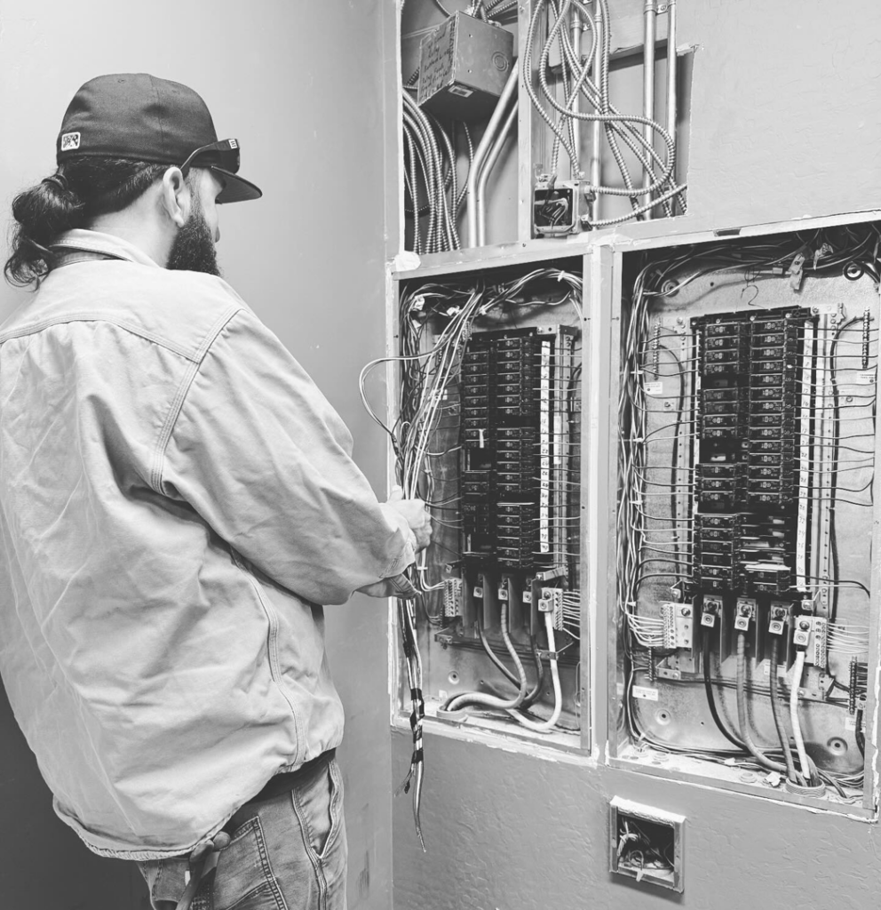 An electrician from Reuben Electrical Contracting working on an electrical breaker panel in Scottsdale, AZ.
