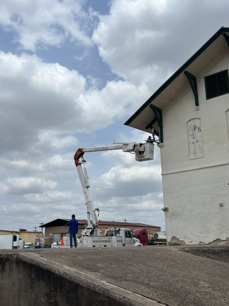 An electrician from Jesse's Electric working from a bucket truck on the exterior of a building in Laredo, TX.