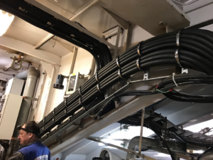 An electrician from Elmore Electric in Dover, IL, meticulously working on bundled electrical cables.
