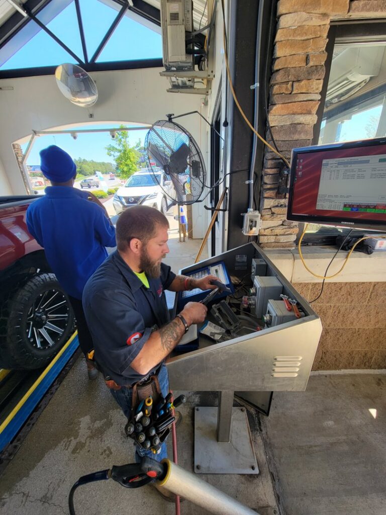An electrician troubleshooting a control panel at a car wash facility for Sherrill Company, LLC Electrical Contractors in Columbus, GA.