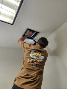 An electrician from Bee Thumb Electric in North Highlands, CA, working on a ceiling fixture or vent.