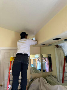 An Electricode electrician on a ladder working on a ceiling fixture or wiring in a bedroom in Las Vegas, NV.