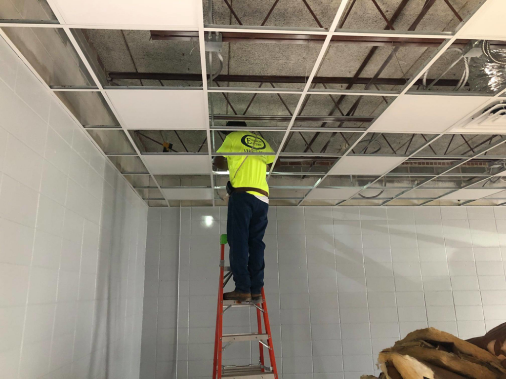 An electrician from Eastmont Electric Company, Inc. on a ladder working on a ceiling grid in Montgomery, AL.