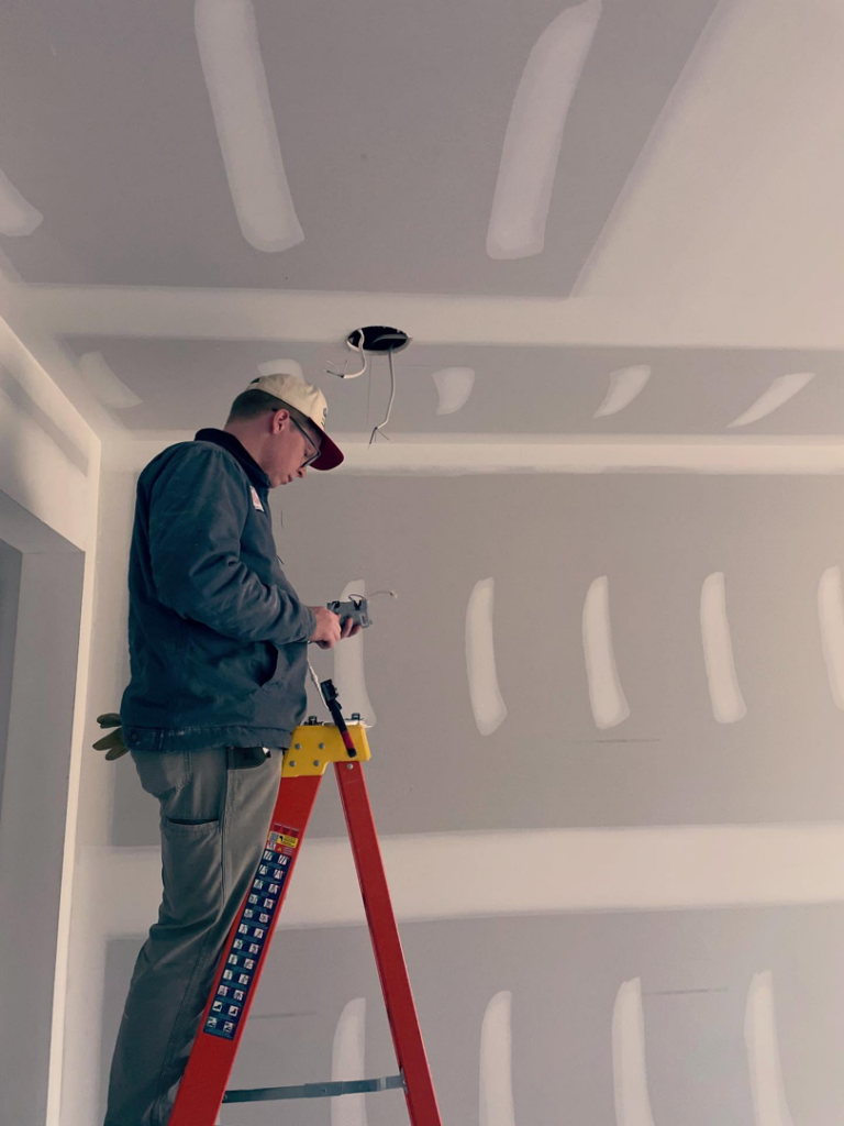 An electrician from Revamp Athens Electrical Company working on ceiling wiring in Athens, GA.