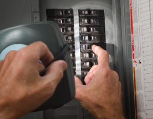 An electrician working on a circuit breaker panel for Four Corners Electric Co., Inc. in Farmington, NM