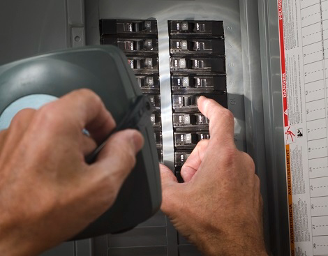 An electrician working on a circuit breaker panel for Four Corners Electric Co., Inc. in Farmington, NM