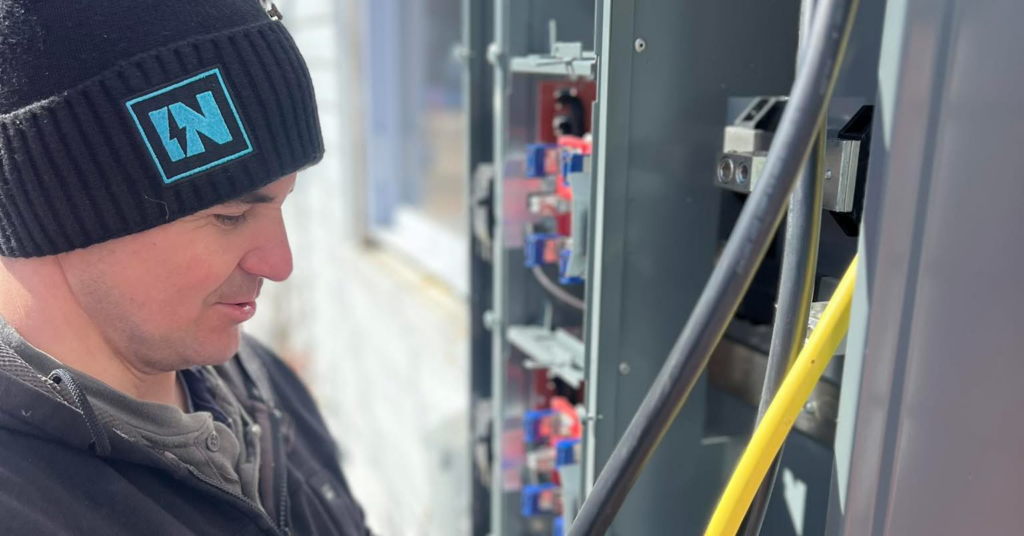 An electrician from IN Power Electric working on an open circuit breaker panel in Gorham, ME