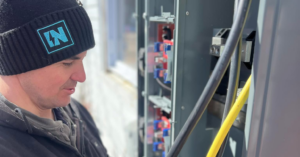 An electrician from IN Power Electric working on an open circuit breaker panel in Gorham, ME