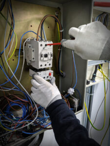 Electrician's gloved hands working on complex wiring inside a panel for Omni Power Electrical Services LLC in San Antonio, TX