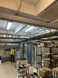 An electrician working on overhead electrical conduit and wiring in a commercial building by Top Tier Electrical Services LLC in Knoxville, TN