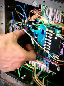 An electrician working on complex wiring and circuit boards inside a control panel for Lightningwerks Electrical in Springfield, MO.