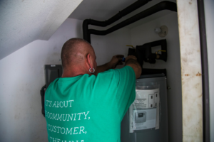 An electrician working on an electric water heater at a home in Pearl City, HI, by Alternate Energy Inc.