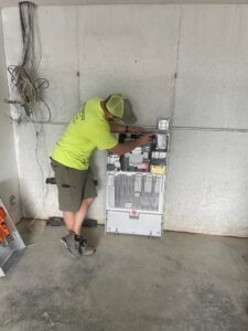 An electrician from Amped Electric working on an electrical inverter system in Virginia Beach, VA.