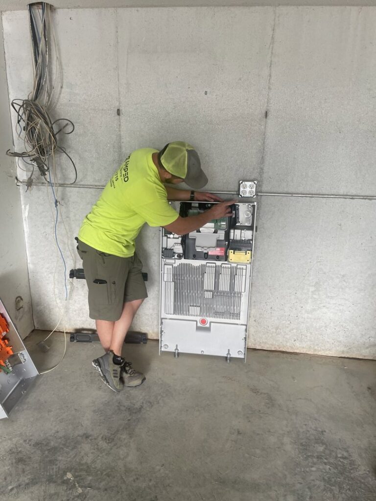 An electrician from Amped Electric working on an electrical inverter system in Virginia Beach, VA.