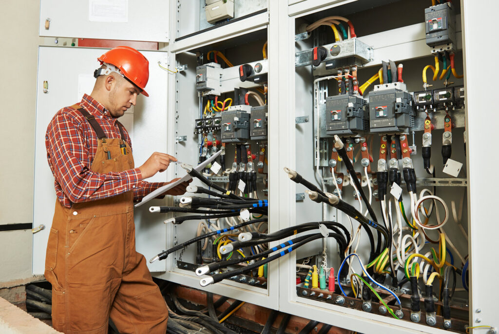 An electrician in a hard hat working on an open electrical panel, representing services by ECS. Electrical Contracting Services LLC in Lake Charles, LA.