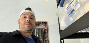 An electrician working on an open electrical panel for Electrician Near Me in Broken Arrow, OK.