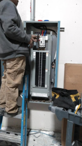 An electrician working on an electrical panel for Grace Electric Co. in Des Moines, IA.