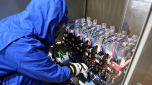 An electrician in protective gear working on an open electrical panel at Hobgood Electric in Winnsboro, SC