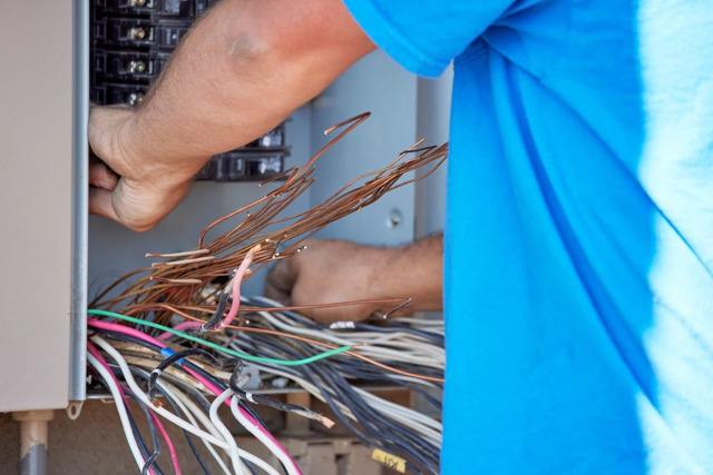 An electrician from Howe Electric Inc working on wiring inside an electrical panel in Tea, SD.