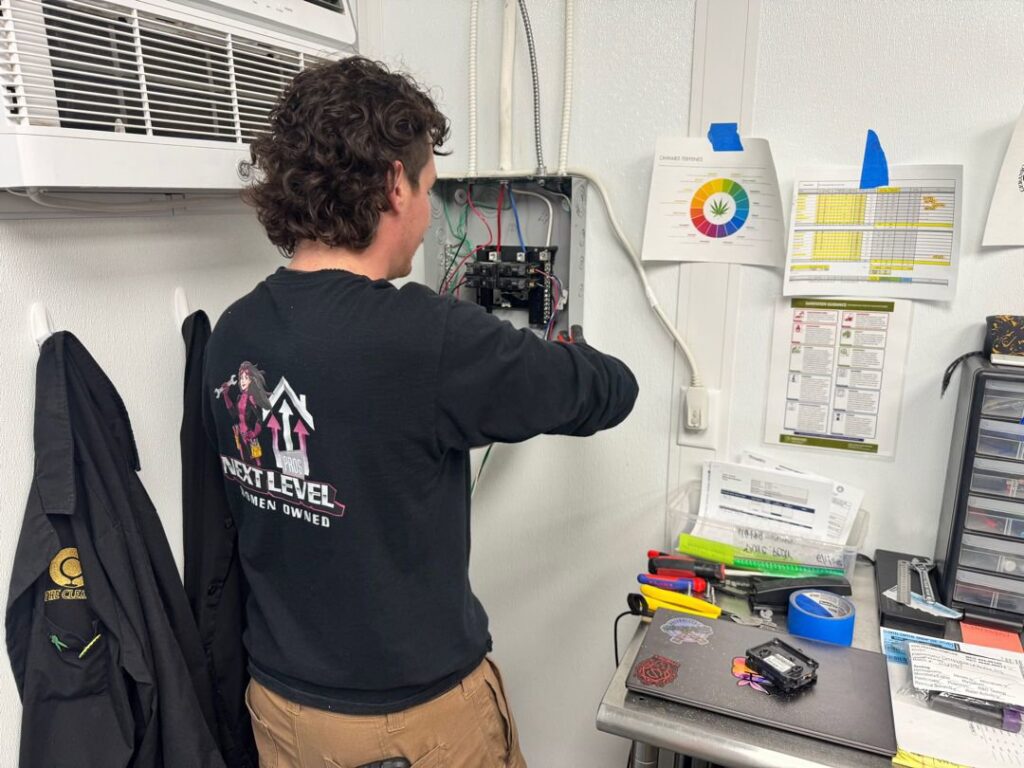 An electrician from Next Level Pros working on an open electrical panel, connecting wires in Lakewood, CO.