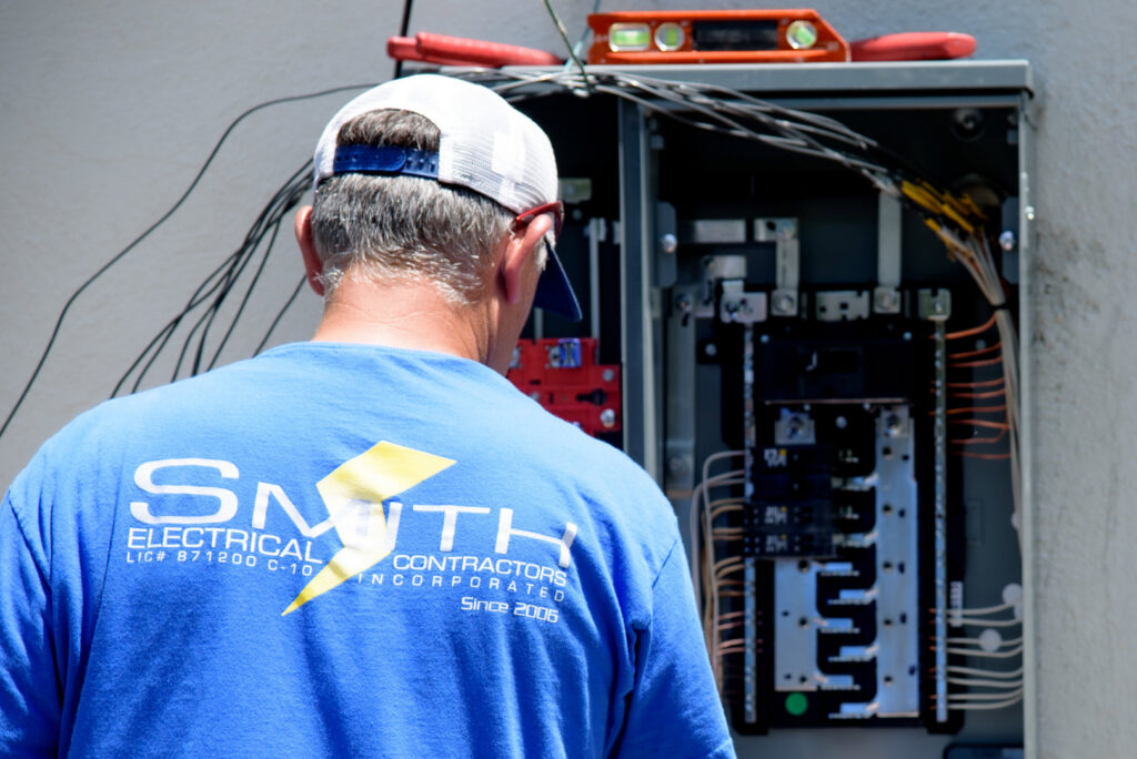 An electrician from Smith Electrical Contractors, Inc. working on an open electrical panel in El Cajon, CA.