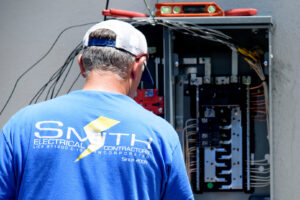 An electrician from Smith Electrical Contractors, Inc. working on an open electrical panel in El Cajon, CA.
