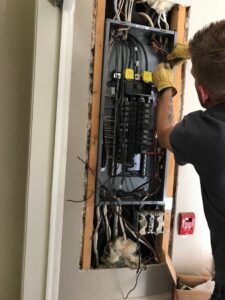 An electrician from The Electric Way in Colorado Springs, CO, working on an open electrical panel.