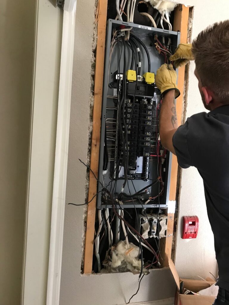 An electrician from The Electric Way in Colorado Springs, CO, working on an open electrical panel.