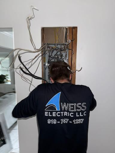 An electrician from Weiss Electric LLC working on an electrical panel with exposed wiring in Saint Charles, MO.