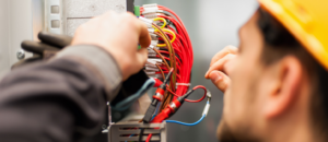 An electrician working on complex wiring inside an electrical panel for WireMasters Electric, Inc. in Miami, FL.