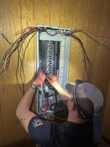 An electrician from Ardent Electric working on wiring an electrical panel in Erie, PA.