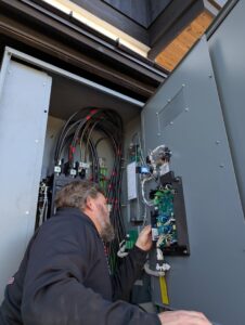 An electrician working on complex wiring inside an electrical panel for Great Northern Power in Kalispell, MT.