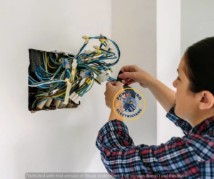 An electrician working on exposed electrical wiring in a wall, providing service for Power Pro Electricians Roanoke, VA