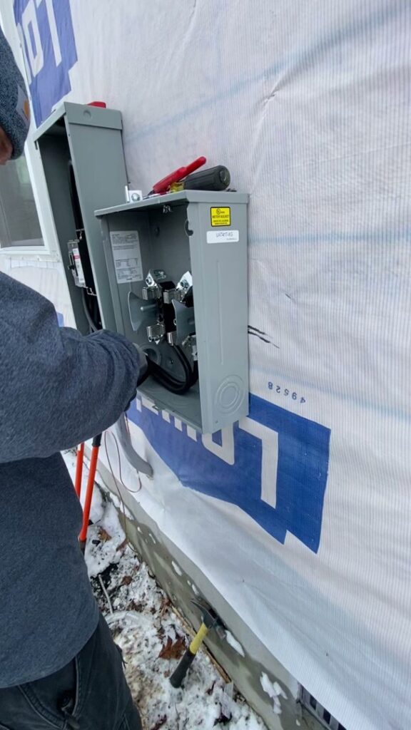 An electrician from CLB Electrical LLC working on an exterior electrical panel during a service call in Townsend, DE.