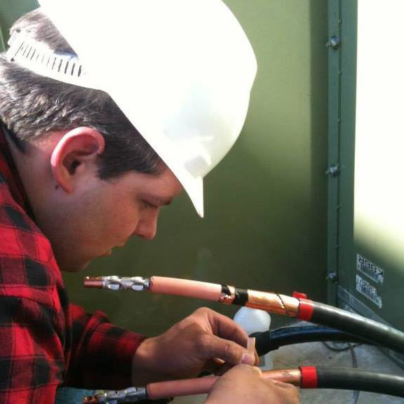 An AccuTex Electric electrician in a hard hat working on heavy-duty electrical cables in Fort Worth, TX.