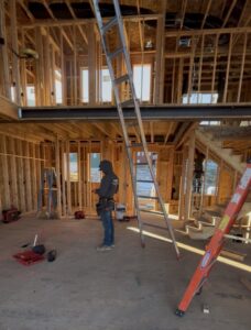 An electrician with a tool belt working on the framing of a new house construction project by Homestead Electric in Orem, UT.